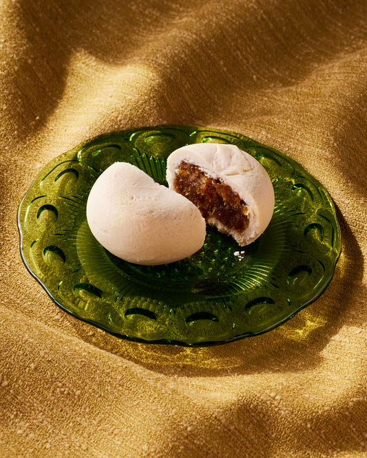 A Taiwanese pineapple cake with a soft shortbread exterior and a sweet pineapple filling, presented on a green plate.